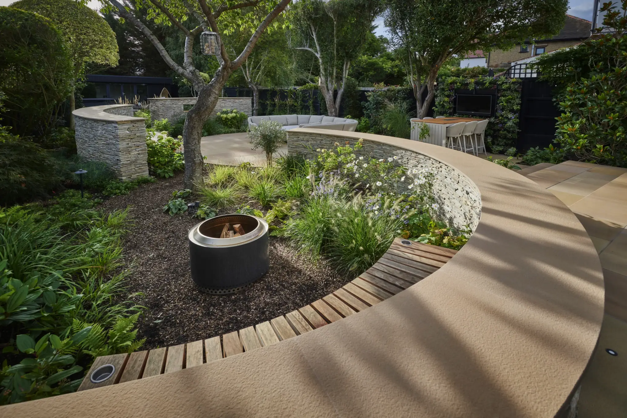 Curved stone walls, terraced paving and garden structure built by Refined Landscapes