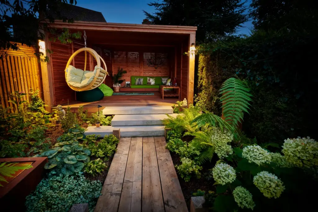 Garden pavilion at twilight with hanging seat and hydrangea planting