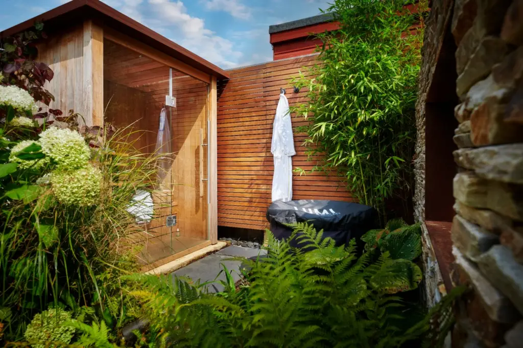 Glass-fronted sauna cabin with cedar cladding and cold plunge tub