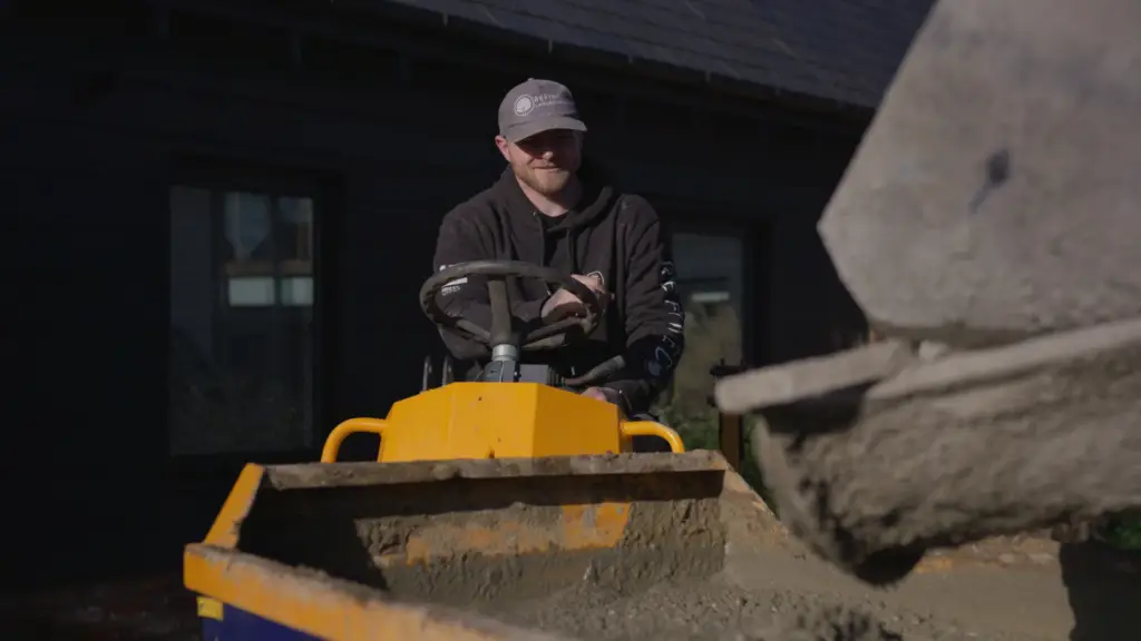 A Refined Landscapes team member driving a dumper as concrete is tipped from the mixer