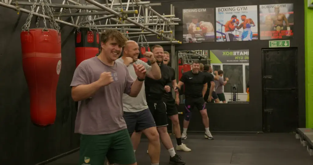 Five members of the team in boxing stances beside the punchbags at the gym