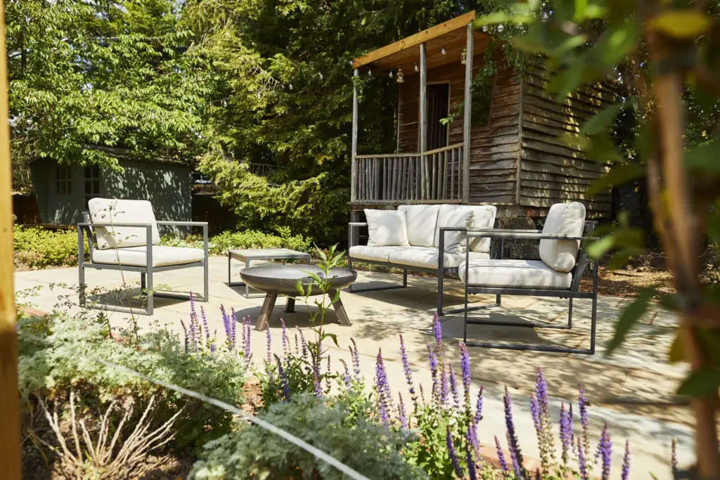 Seating and a fire bowl in front of the timber summerhouse with salvia in flower