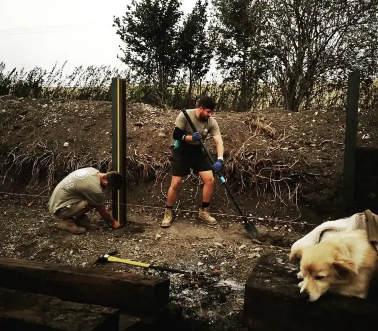 Jacob Berry and a colleague setting fence posts in the early days of Refined Landscapes, the dog looking on