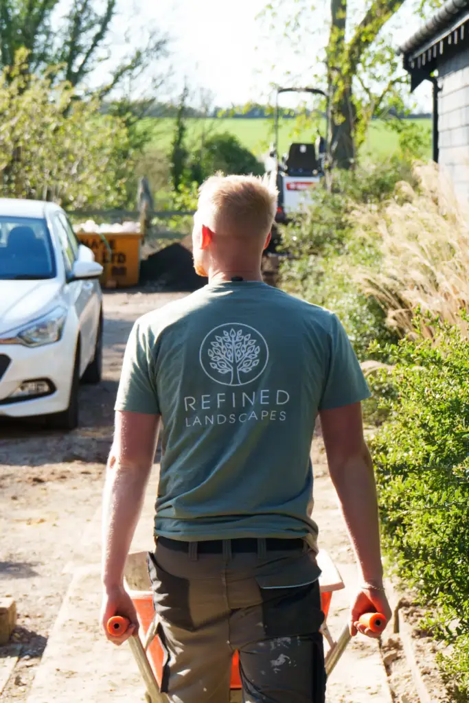 Two members of the Refined Landscapes team laughing on site beside a newly lined pond
