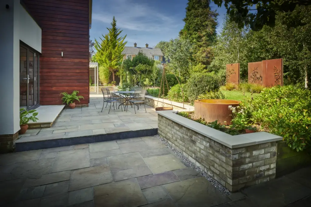 Brick-faced raised bed with pencil-round copings beside the house