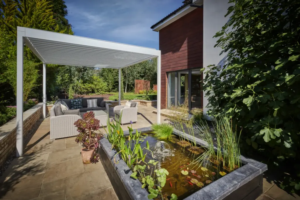 Raised water feature with aquatic planting beside the pergola seating