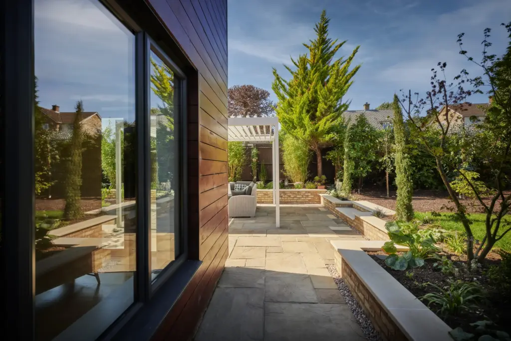 Bullnose steps and terrace running along the side of the house towards the pergola
