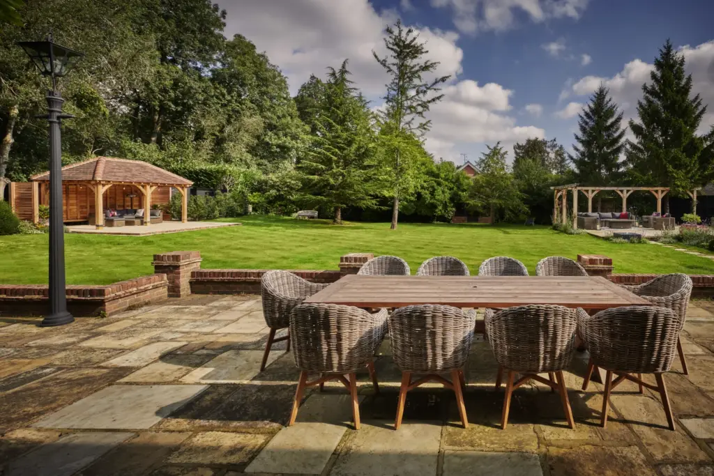 Outdoor dining table on the stone terrace with the lawn and gazebo beyond