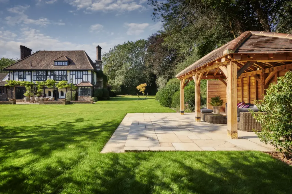 Oak-framed gazebo on a stone terrace across the lawn from the house