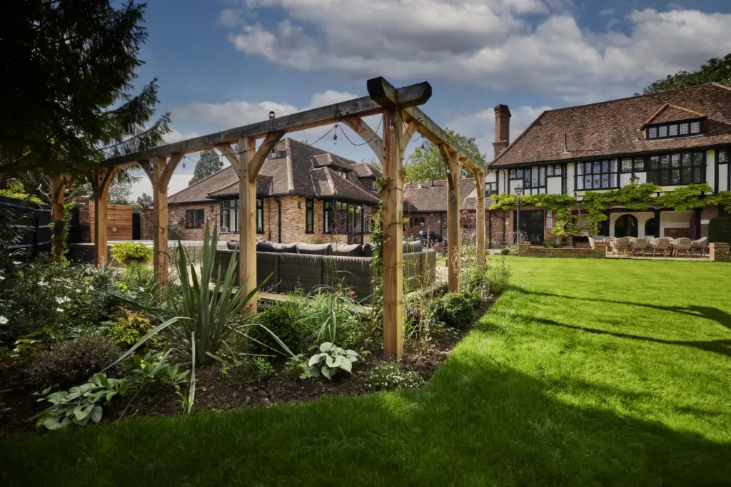 Oak pergola post with layered planting and the house beyond