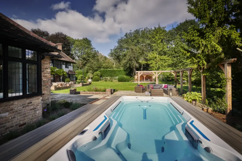 Partially sunk swim spa on a timber deck beside the house