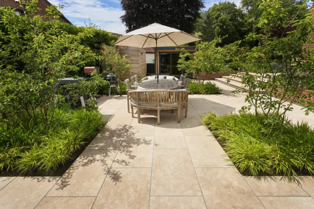 The formal dining terrace under a parasol, softened by grasses and perennial planting