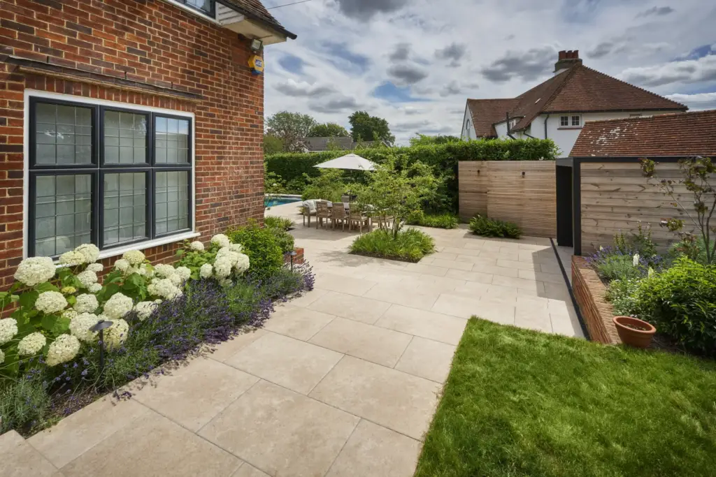 White hydrangeas and lavender beside the house, with the terrace and garden room beyond