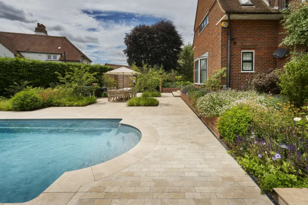 Limestone cobble paving curving around the Roman end of the pool, with layered planting at its edge