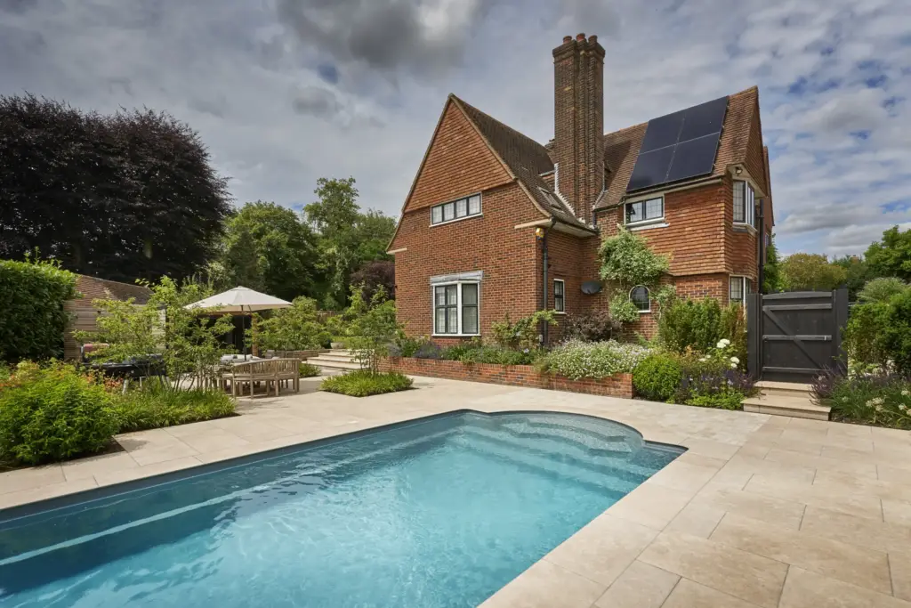 The Roman end of the pool beside the house, with the dining terrace under a parasol beyond